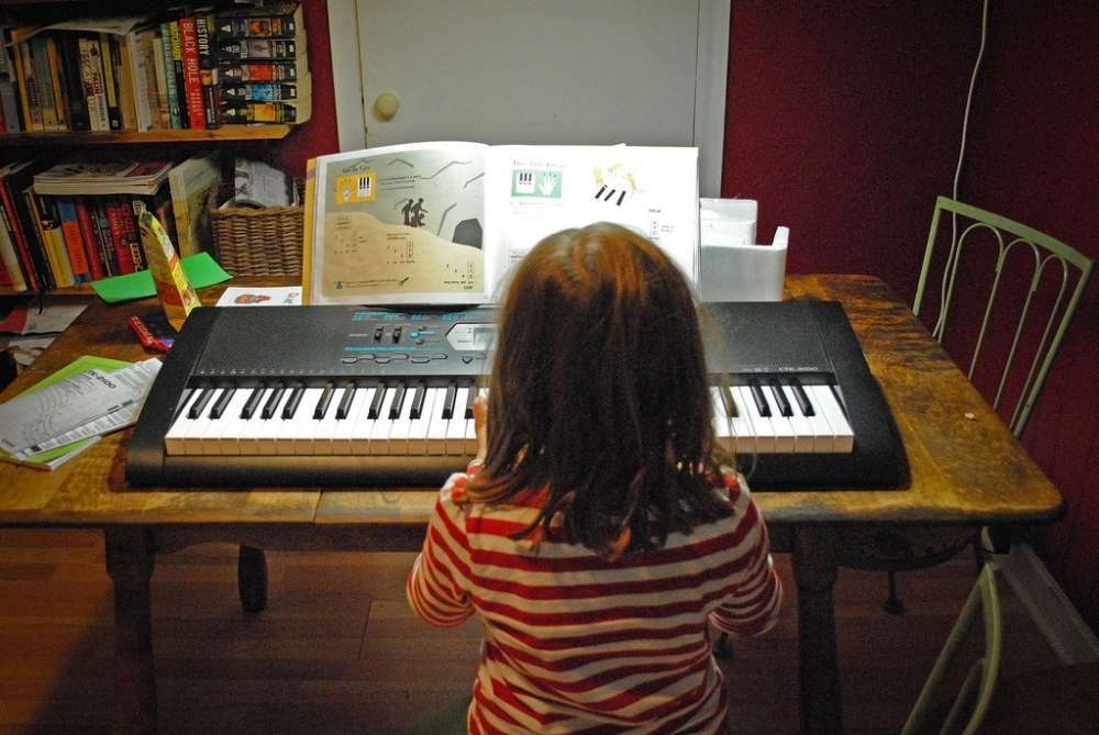 child practicing keyboard